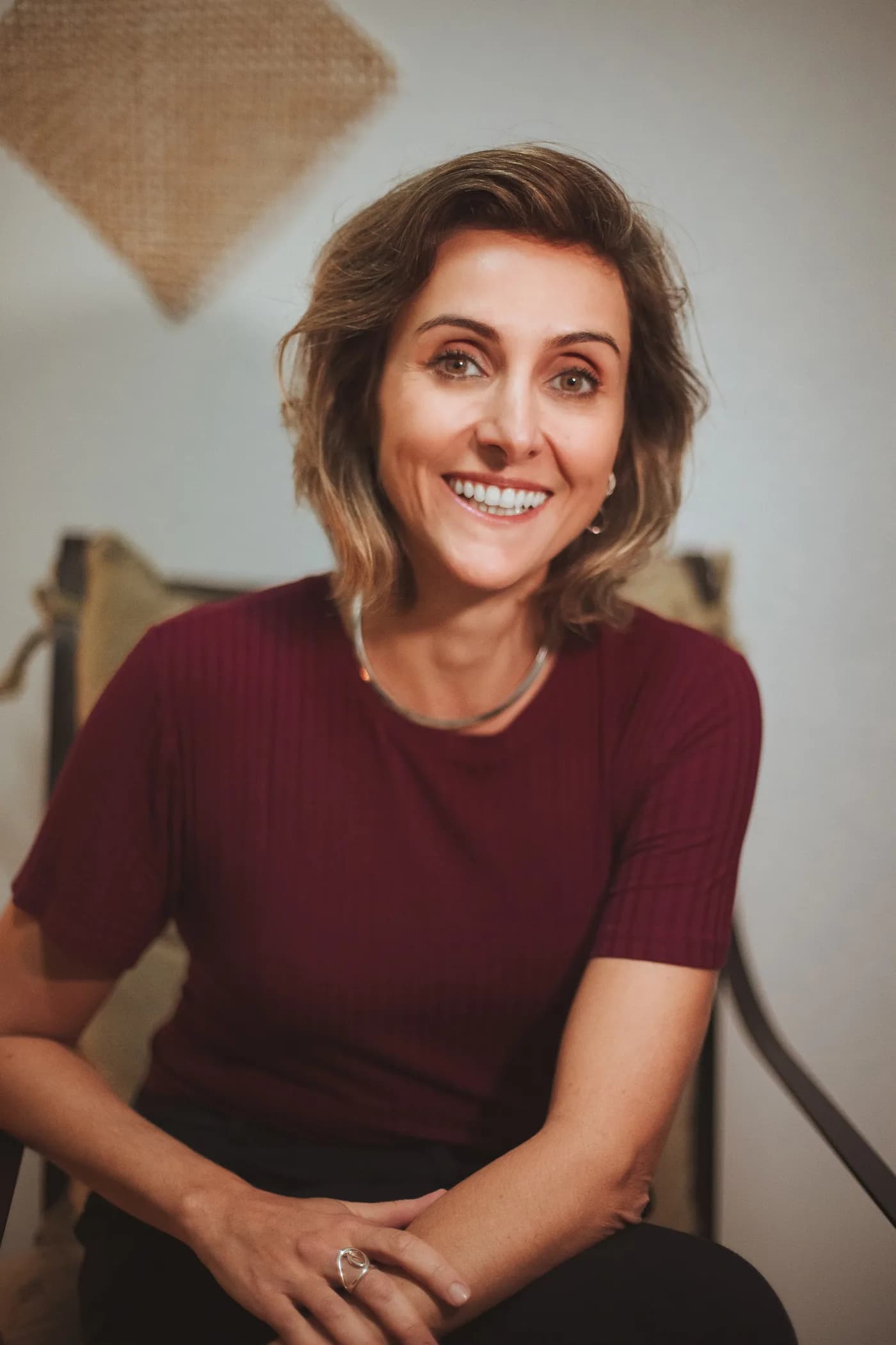 Caroline Reis Pereira, psicóloga, sorrindo sentada em seu consultório